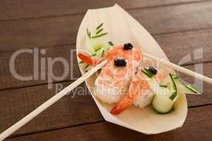 Three nigiri sushi served with chopsticks in wooden boat plate