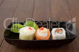 Nigiri and uramaki sushi served on black boat plate