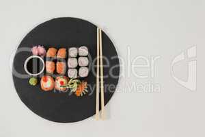 Set of assorted sushi served on black stone slate with soy sauce and chopsticks