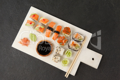 Assorted sushi set served with soy sauce and chopsticks on white board