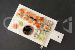 Assorted sushi set served with soy sauce and chopsticks on white board