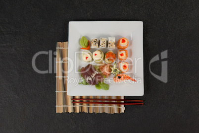 Assorted sushi set served with chopsticks in white plate on sushi mat