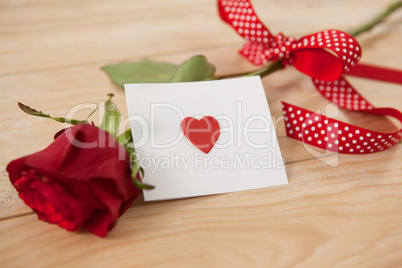 Red rose wrapped in ribbon and heart printed envelope
