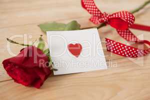 Red rose wrapped in ribbon and heart printed envelope