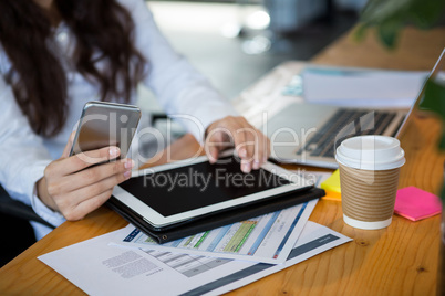 Business executive using digital tablet and mobile phone at desk
