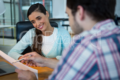 Smiling business executives discussing over document