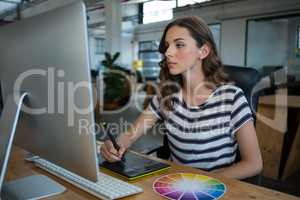 Female graphic designer using graphics tablet at desk