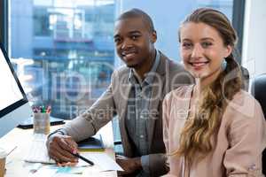 Portrait of graphic designer at desk with colleague