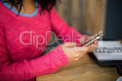 Woman sitting at table and using mobile phone in cafÃ?Â©