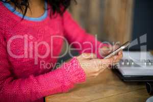 Woman sitting at table and using mobile phone in cafÃ?Â©