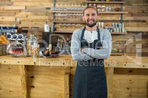 Portrait of waiter standing with arms crossed at counter
