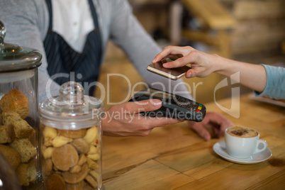 Woman paying bill through smartphone using NFC technology