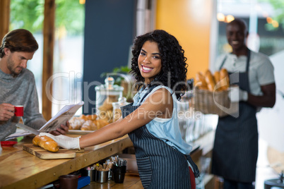 Portrait of waitress serving at counter in cafÃ?Â©