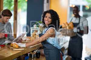 Portrait of waitress serving at counter in cafÃ?Â©