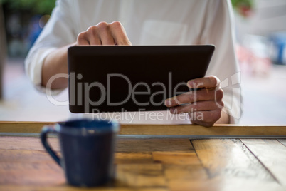 Mid-section of man using digital tablet at counter