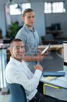 Portrait of smiling businessmen at desk