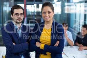 Male and female business executive standing with arms crossed
