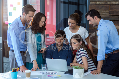 Team of graphic designers discussing over laptop