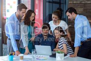 Team of graphic designers discussing over laptop