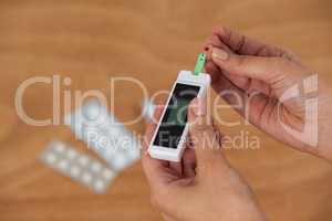 Close-up of woman hands testing blood sugar with glucometer