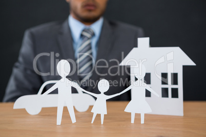 Paper cut out family chain with car and house at desk