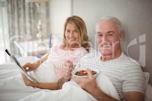 Portrait of smiling couple reading newspaper while having breakfast