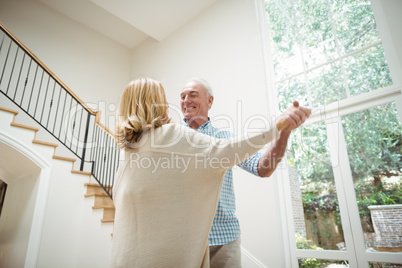 Senior couple dancing together in living room