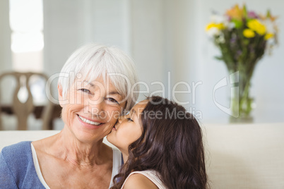Granddaughter kissing grandmother on cheek in living room