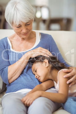 Granddaughter sleeping on grandmothers lap in living room