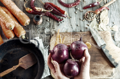 three large red onions in female hands