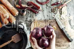 three large red onions in female hands