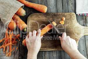 process of cutting slices of carrot on a kitchen wooden board