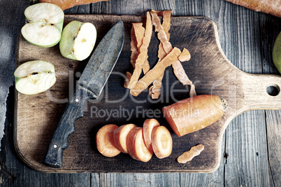 Cut carrots and sliced green apple on a kitchen board