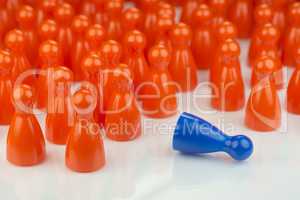 Conceptual orange game pawns and a blue play pawn