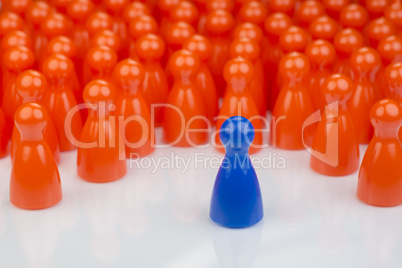 Conceptual orange game pawns and a blue play pawn