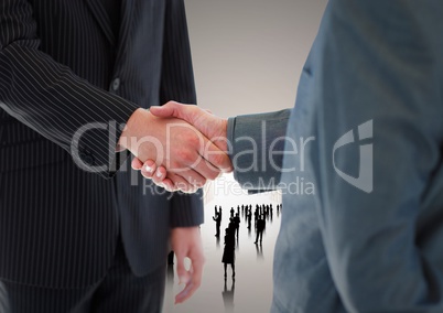Composite image of Handshake in front of silhouette business people