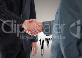 Composite image of Handshake in front of silhouette business people