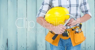 Composite image of Carpenter torso with hammer against blue wood panel
