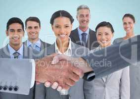 Composite image of Handshake in front of business people with blue background
