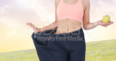 Fitness woman Torso wearing a huge trouser and holding an apple to show her diet to lose weight