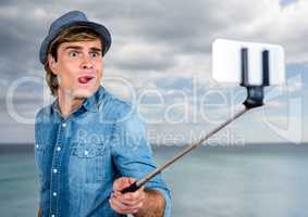 Man with selfie stick in front of sea
