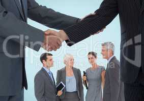 Handshake in front of business people against blue background