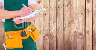 Composite image of Carpenter with clipboard against wood panel