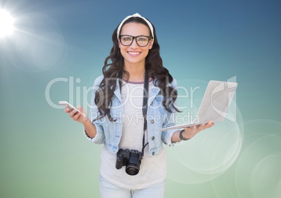 Woman with phone and laptop against blue green background with flare
