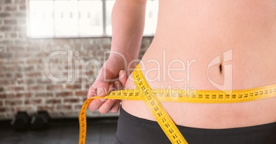 Fitness woman waist who is measuring her size in a gym