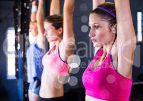 Fitness women doing pull ups with bokeh in a gym