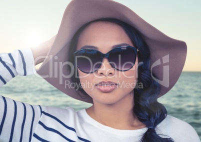 Composite image of Woman in summer hat against sea with flare