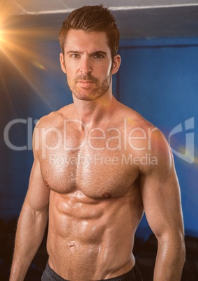 Body builder with flare against a blue wall