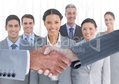 Handshake in front of business people in office against white background