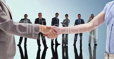 Handshake in front of business people with blue background